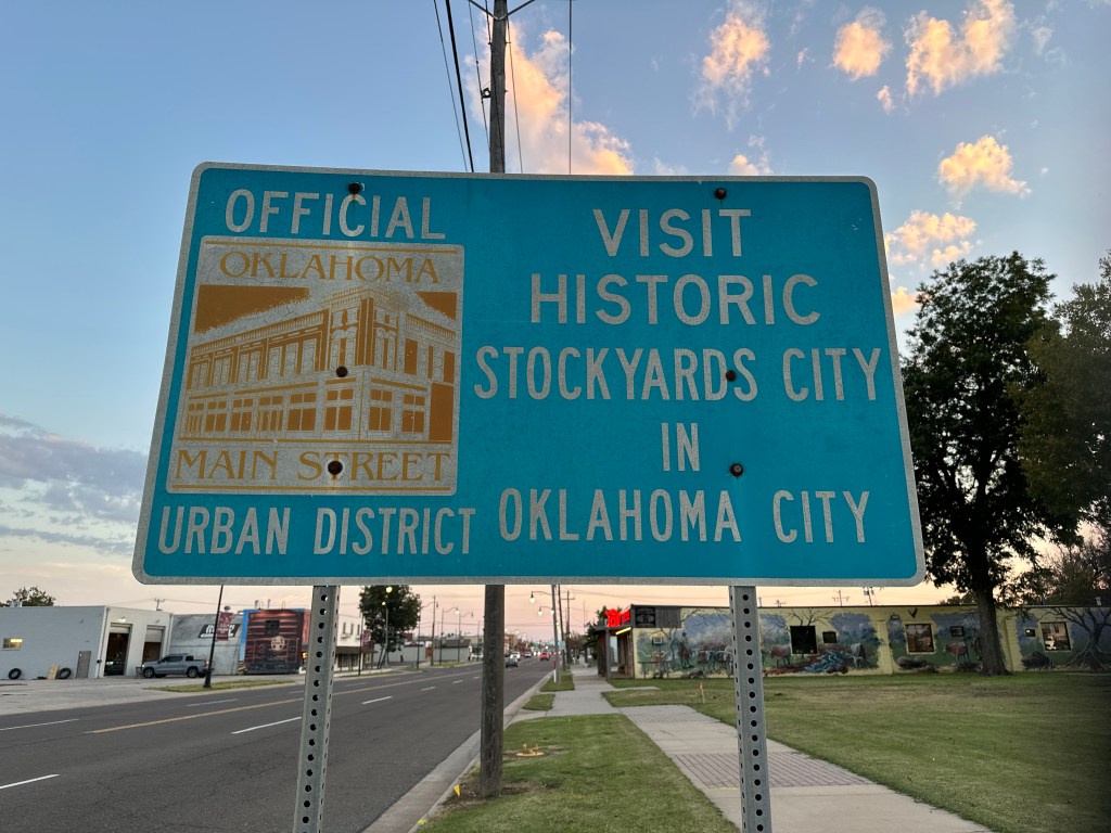 Official Oklahoma sign promoting Historic Stockyards City in Oklahoma City, featuring a vintage building illustration.