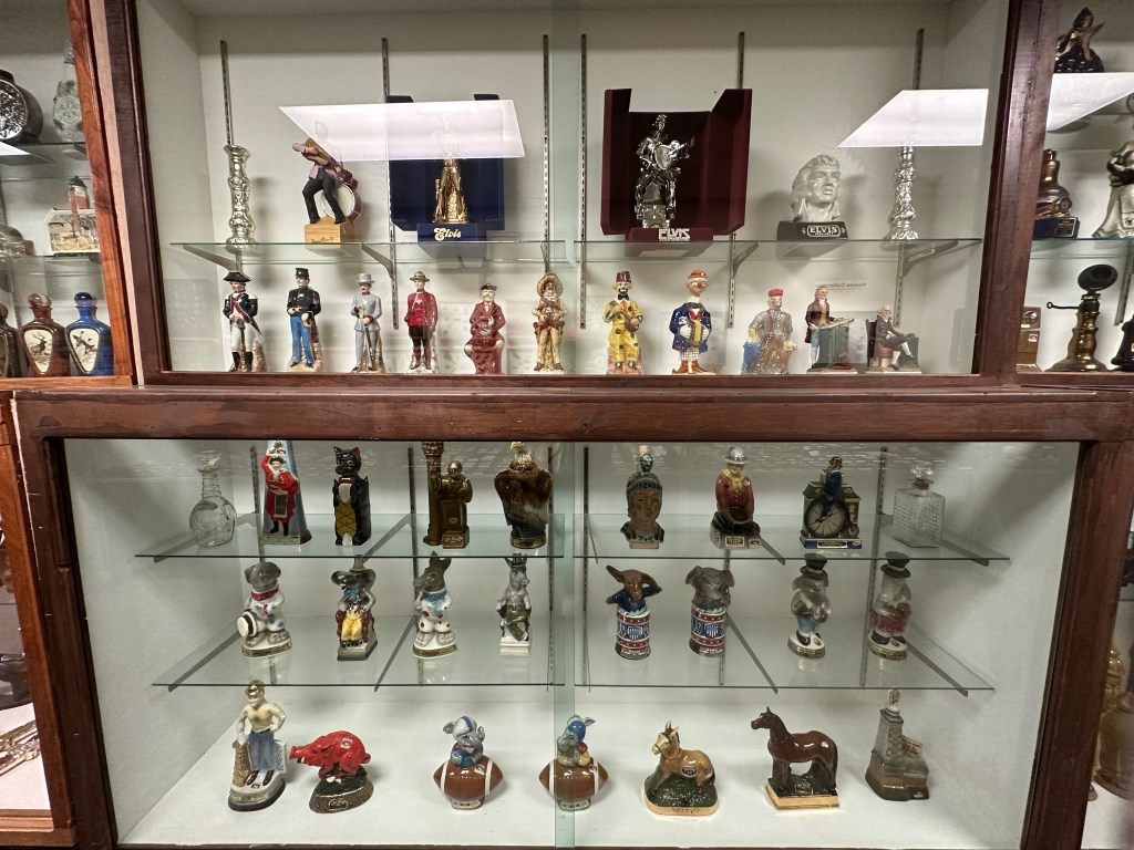 Display of various figurines and collectibles, including a mix of people, animals, and themed items in a glass cabinet at the D.W. Correll Museum.