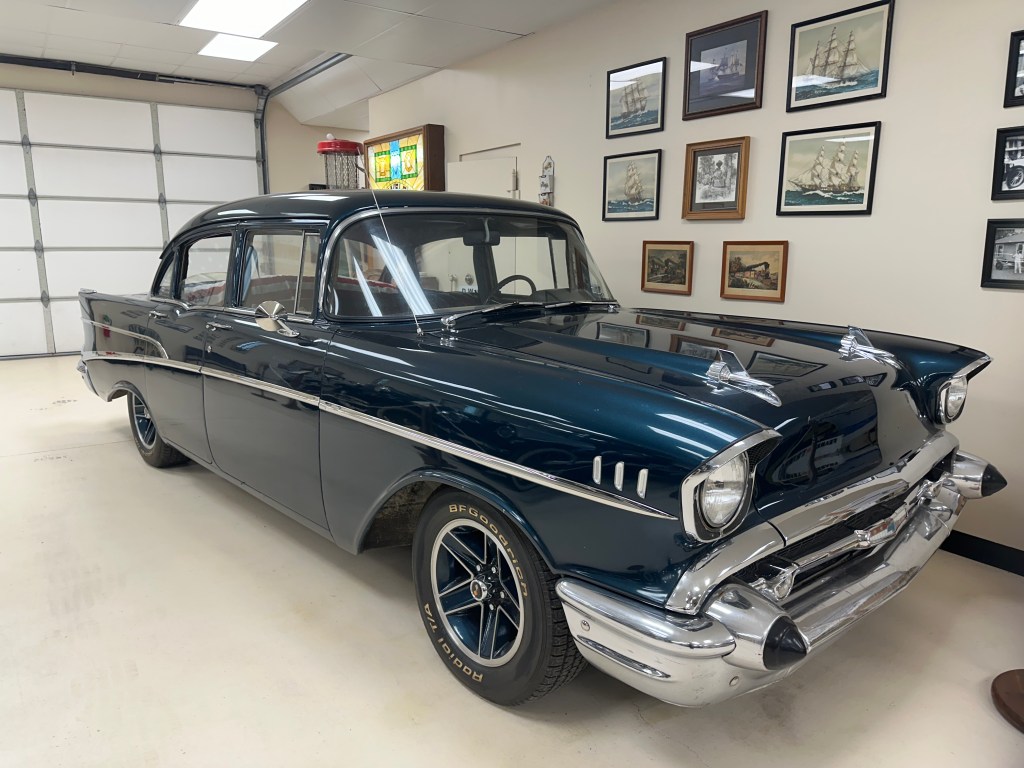 A vintage 1957 Chevrolet car displayed inside the D.W. Correll Museum, with framed maritime art in the background.