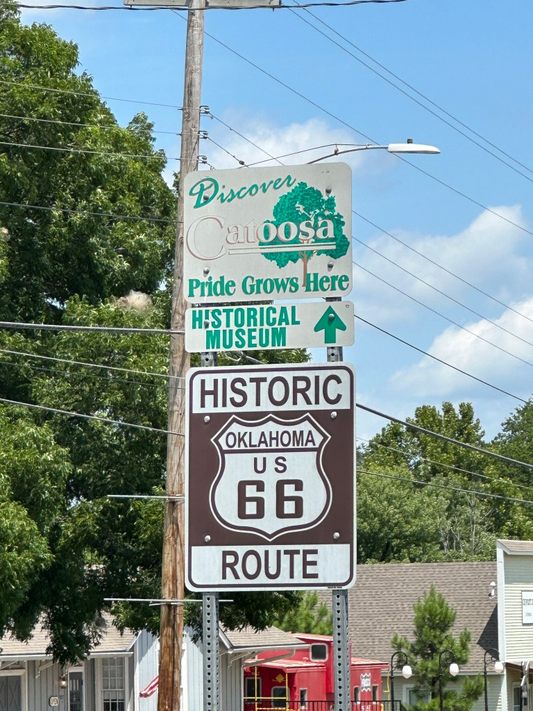 Sign indicating the Historical Museum in Catoosa, Oklahoma, featuring the phrase 'Discover Catoosa' and 'Pride Grows Here,' alongside a historic Route 66 sign.