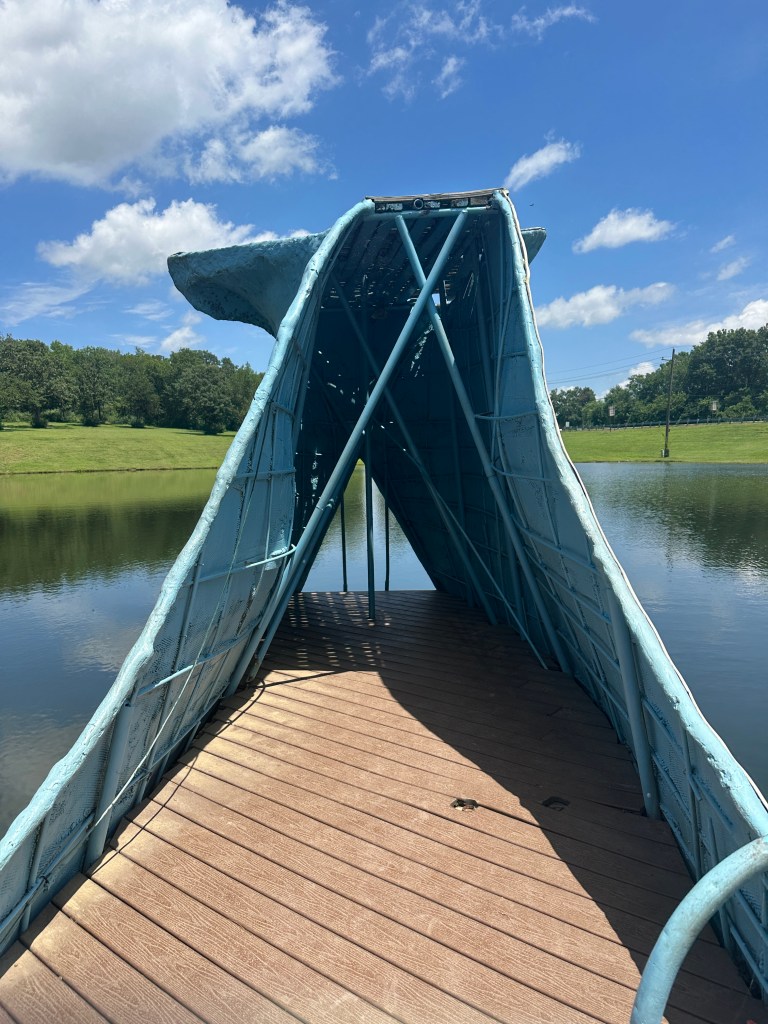 Interior view of the Blue Whale in Catoosa, Oklahoma, showcasing its blue structure and wooden flooring, set against a pond and grassy background.