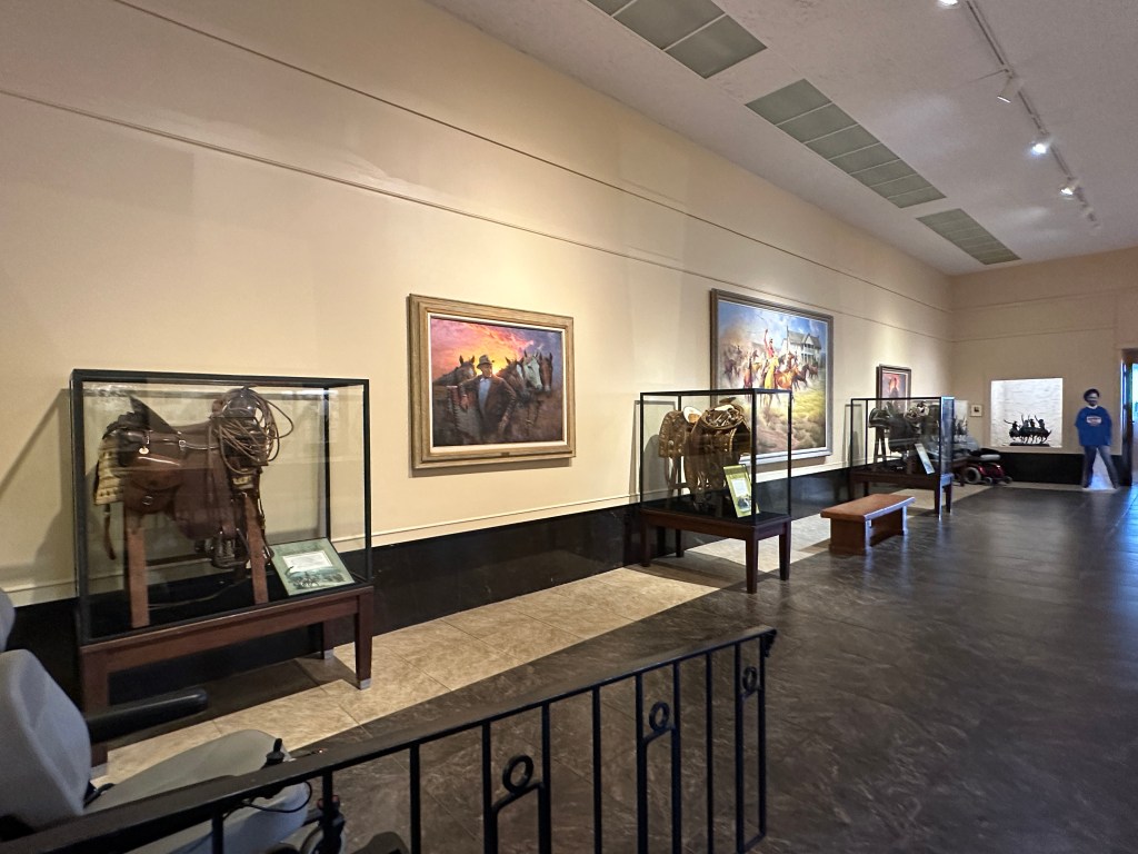 Interior view of the Will Rogers Memorial Museum showcasing saddles and paintings on display.