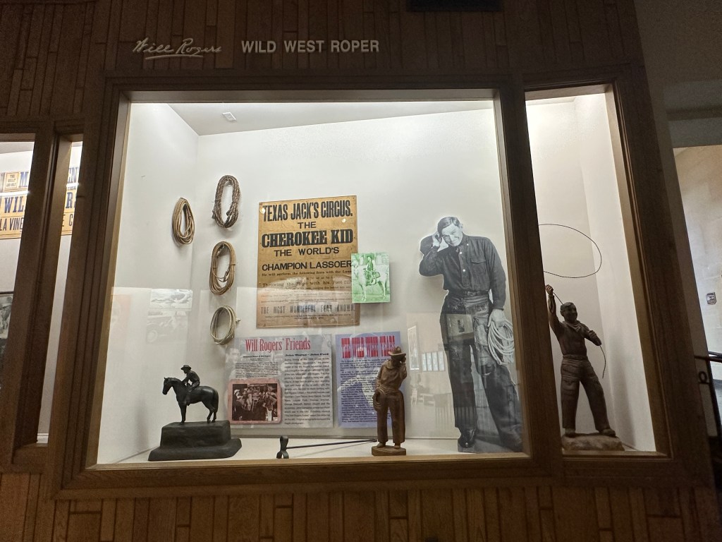 Display case featuring memorabilia related to Wild West roping, including ropes, figurines, and historical photographs.