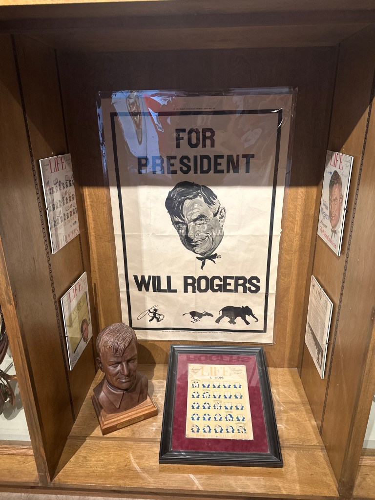 Display showcasing memorabilia related to Will Rogers, including a poster reading 'For President', a bust of Will Rogers, and various editions of Life magazine featuring him.