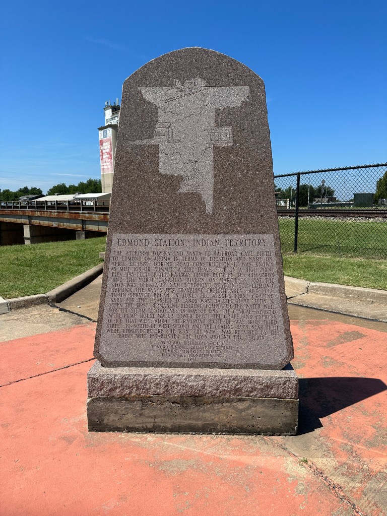 Historical marker for Edmond Station located in the Edmond Festival Market Place parking lot in Oklahoma, featuring an engraved map and text about the station's history.