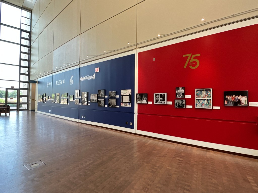 Interior view of the Oklahoma History Center exhibition featuring a blue and red wall display celebrating KFOR's 75th anniversary, with historical photographs and information about Oklahoma's first television station.