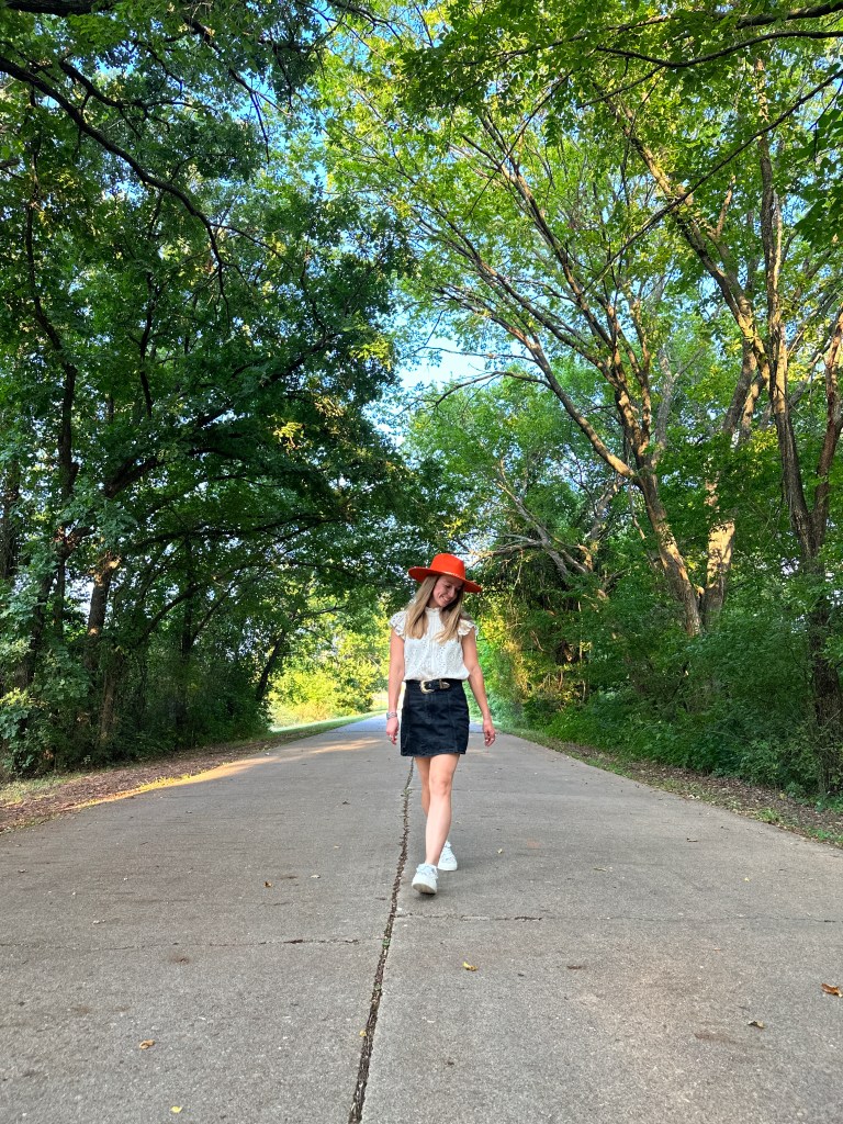 A person walking on a historic stretch of Route 66 in Arcadia, Oklahoma, surrounded by lush greenery and trees.