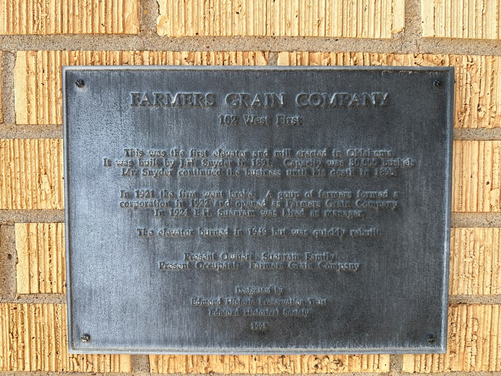 Plaque detailing the history of the Farmers Grain Company in Edmond, Oklahoma, highlighting its founding in 1891 and subsequent events.
