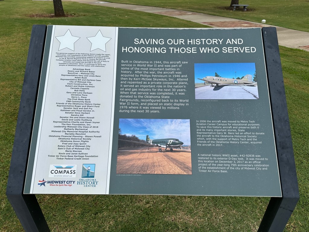 Information plaque about a historic aircraft built in 1944, detailing its service in World War II and subsequent restoration efforts. The plaque includes acknowledgments to supporters and outlines the aircraft's history and educational purposes.