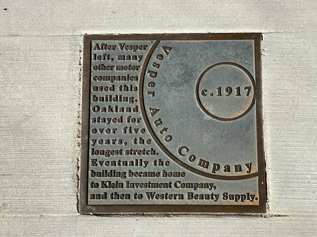 A historic marker plaque for Vesper Auto Company, indicating its use by various motor companies since c. 1917, mounted on a wall.