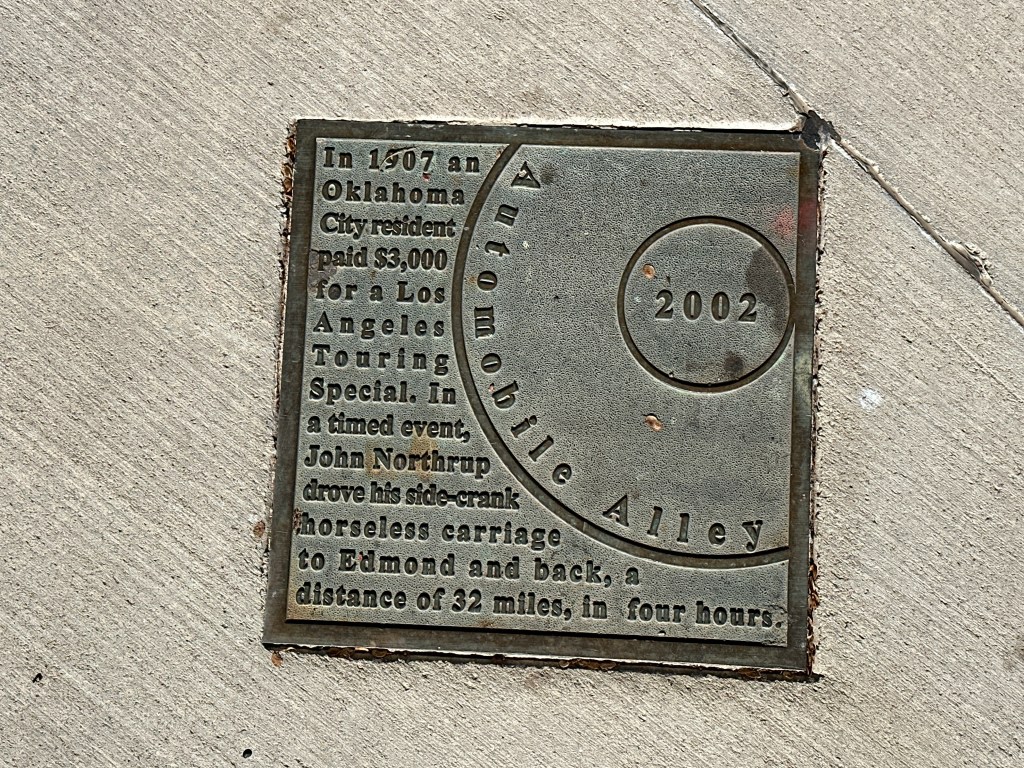 Bronze historic marker plaque for Automobile Alley featuring text about an Oklahoma City resident's 1907 purchase of a Los Angeles Touring Special.