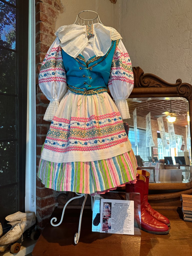 Traditional Polish dance dress displayed in the McLoud Historical Society Museum, featuring vibrant colors and intricate patterns.