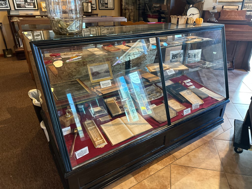 Display case filled with historical artifacts and documents at the McLoud Historical Society Museum.