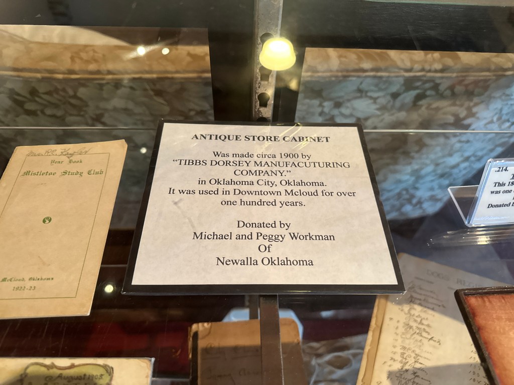 Close-up of an antique store cabinet from circa 1900, displaying a sign detailing its history and donation.