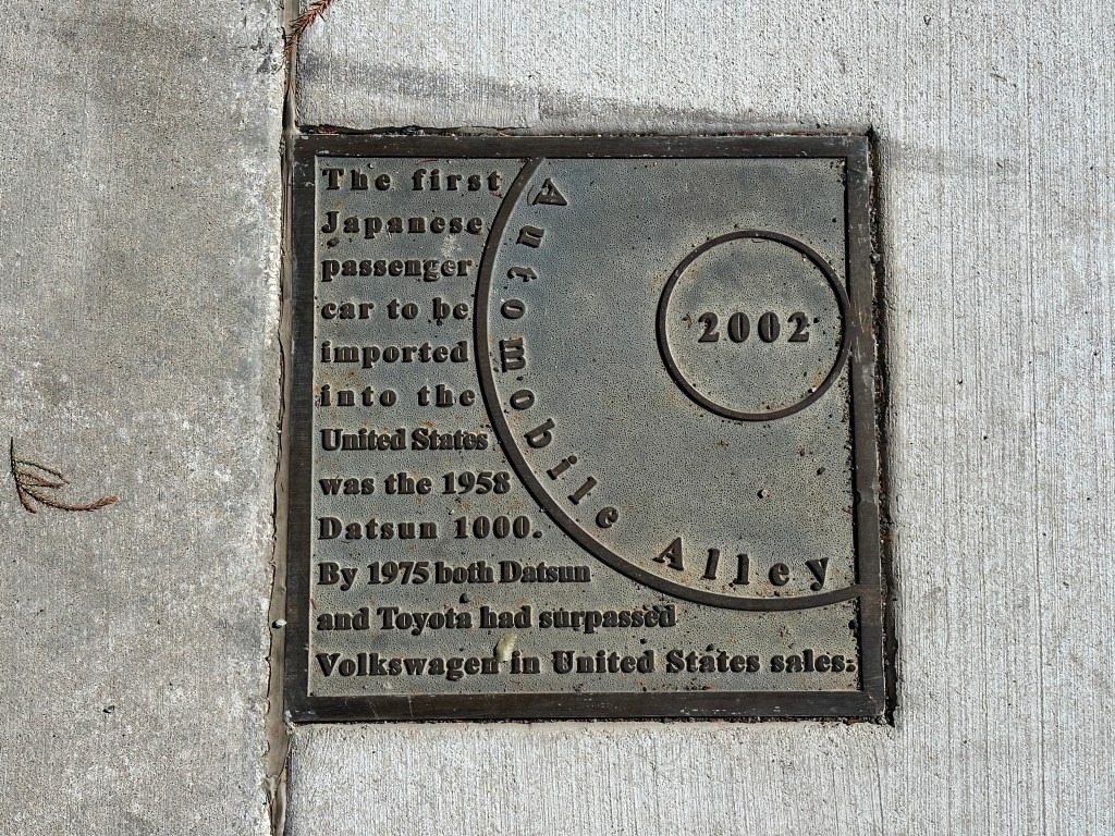 Historic marker plaque on the sidewalk of Automobile Alley, Oklahoma City, detailing the first Japanese passenger car imported to the U.S., the 1958 Datsun 1000.