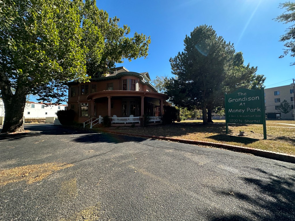 Exterior view of The Grandison at Maney Park, a bed and breakfast inn, showcasing a historic building surrounded by trees, with a sign indicating the establishment's name and address.