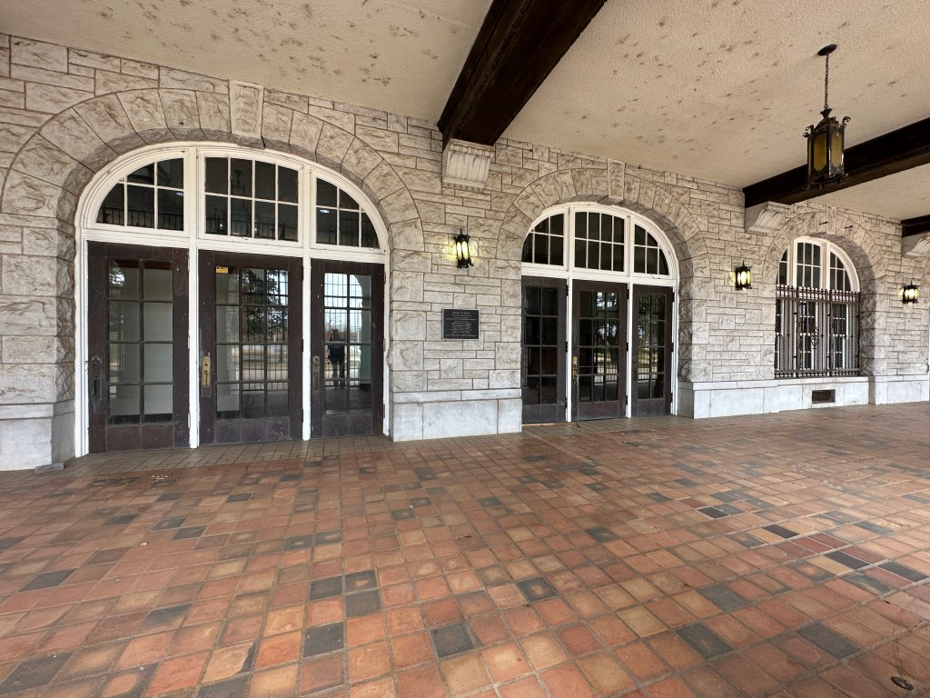 Exterior view of the entrance to the historic Union Station in Oklahoma City, showcasing its stone facade and large arched windows.