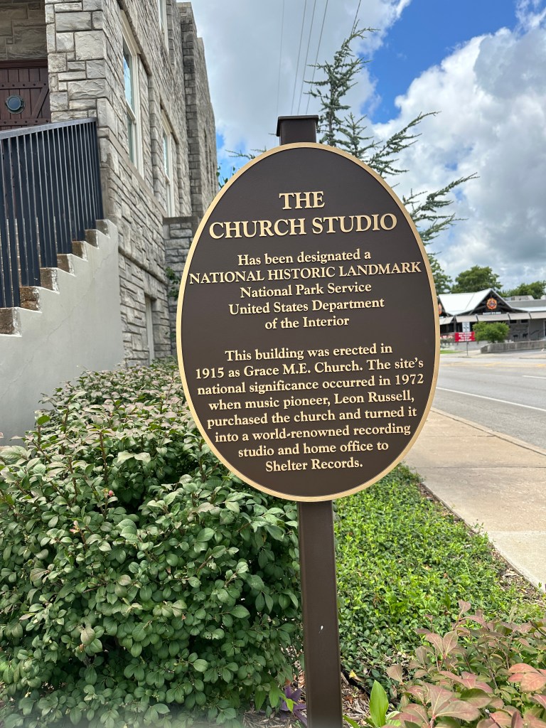 A historic marker sign for The Church Studio in Tulsa, Oklahoma, detailing its designation as a National Historic Landmark and its history as a former church and recording studio.