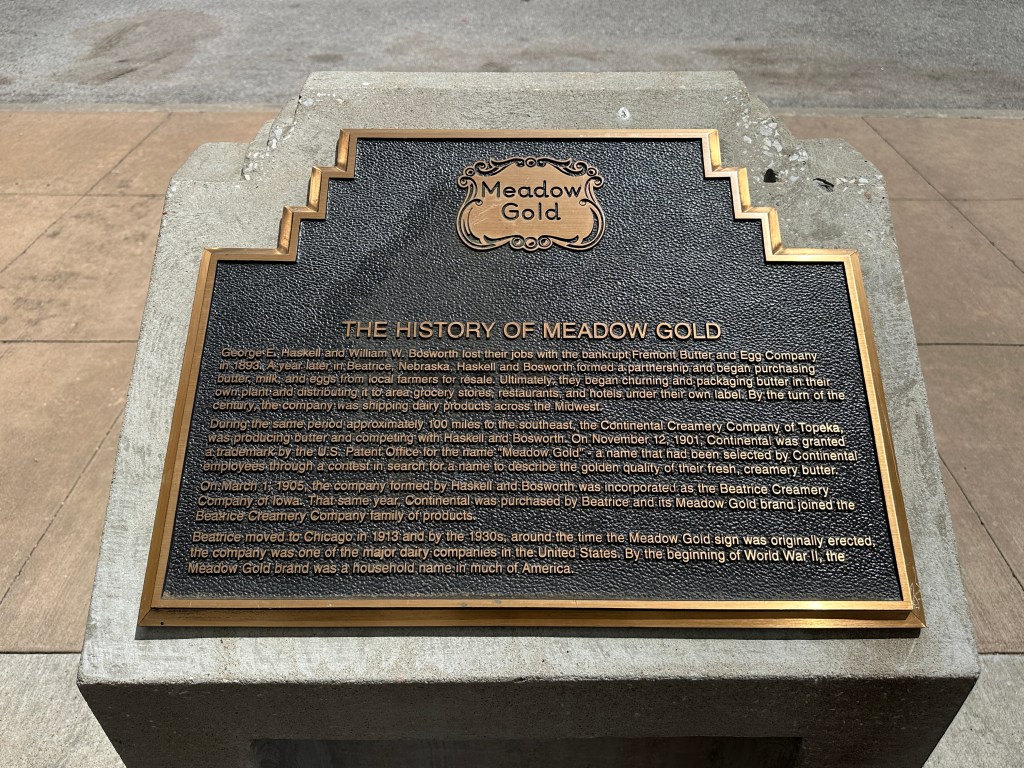 Historical marker plaque detailing the history of Meadow Gold, with engraved text on a metal plate mounted on a stone base.