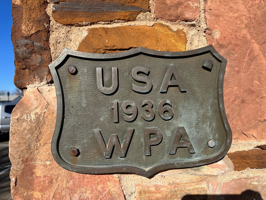 Bronze plaque inscribed with 'USA 1936 WPA' attached to a stone wall.