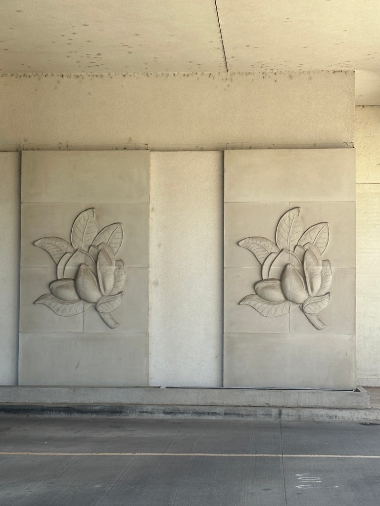 Close-up of decorative relief sculptures of magnolia flowers and leaves on a wall.