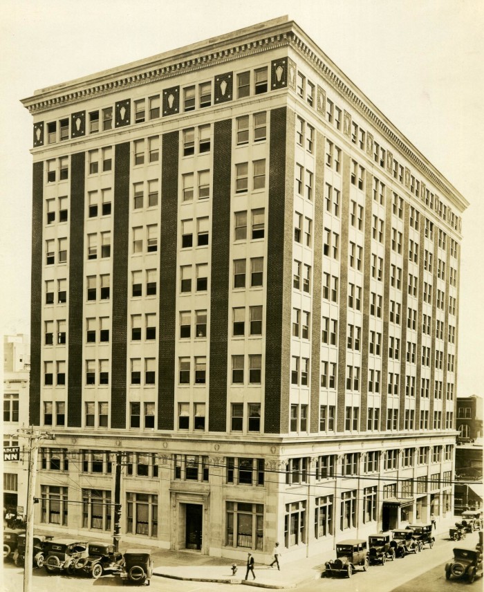 Historic building with a brick facade, featuring multiple floors and large windows, captured in a vintage style.