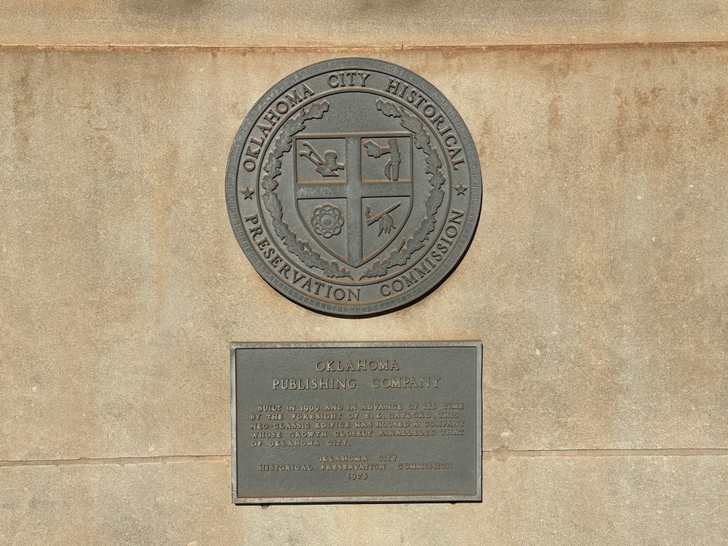 Bronze plaque for the Oklahoma City Historical Preservation Commission, mounted on a wall, detailing the historical significance of the Oklahoma Publishing Company building, established in 1909.