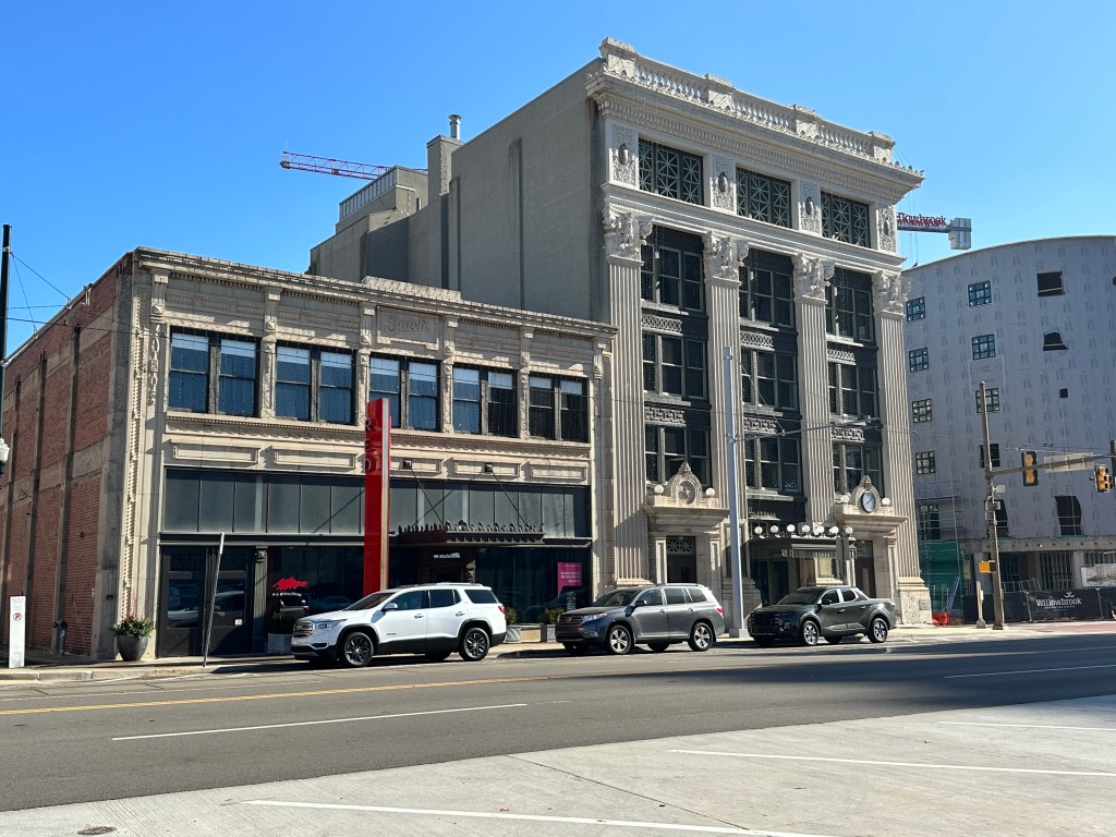 Street view of two historic buildings featuring decorative architecture, with a modern construction site in the background.
