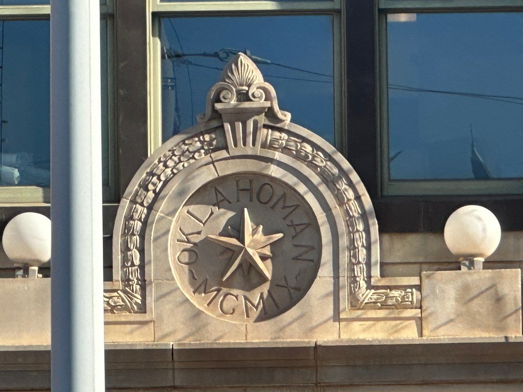 Architectural detail featuring a decorative emblem with the text 'Oklahoma' and the year 'MCMIX', surrounded by a circular design and adorned with a star.