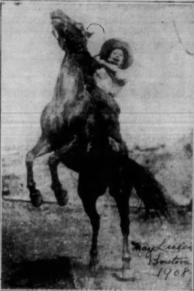 A young child in a large hat appears joyfully riding a rearing horse, captured in a vintage black and white photograph from 1908.