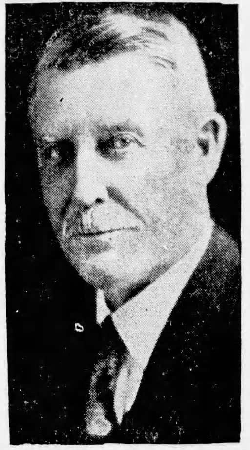 Black and white portrait of an older man with short hair and a light mustache, wearing a suit and tie.