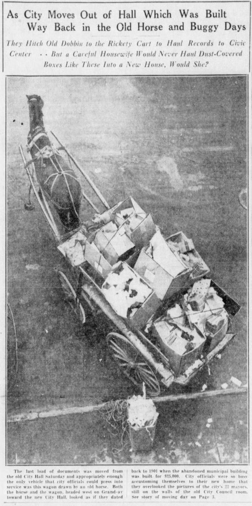 A historic black and white image of a horse-drawn cart loaded with dust-covered boxes, depicting a scene from the old City Hall moving day.